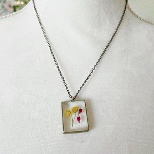 Yellow and pink floral botanical resin necklace in dark silver bezel